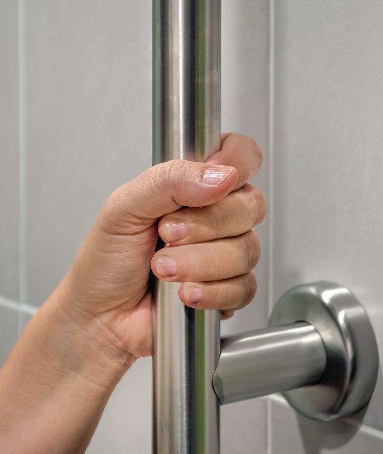 Woman holding on handrail in toilet.